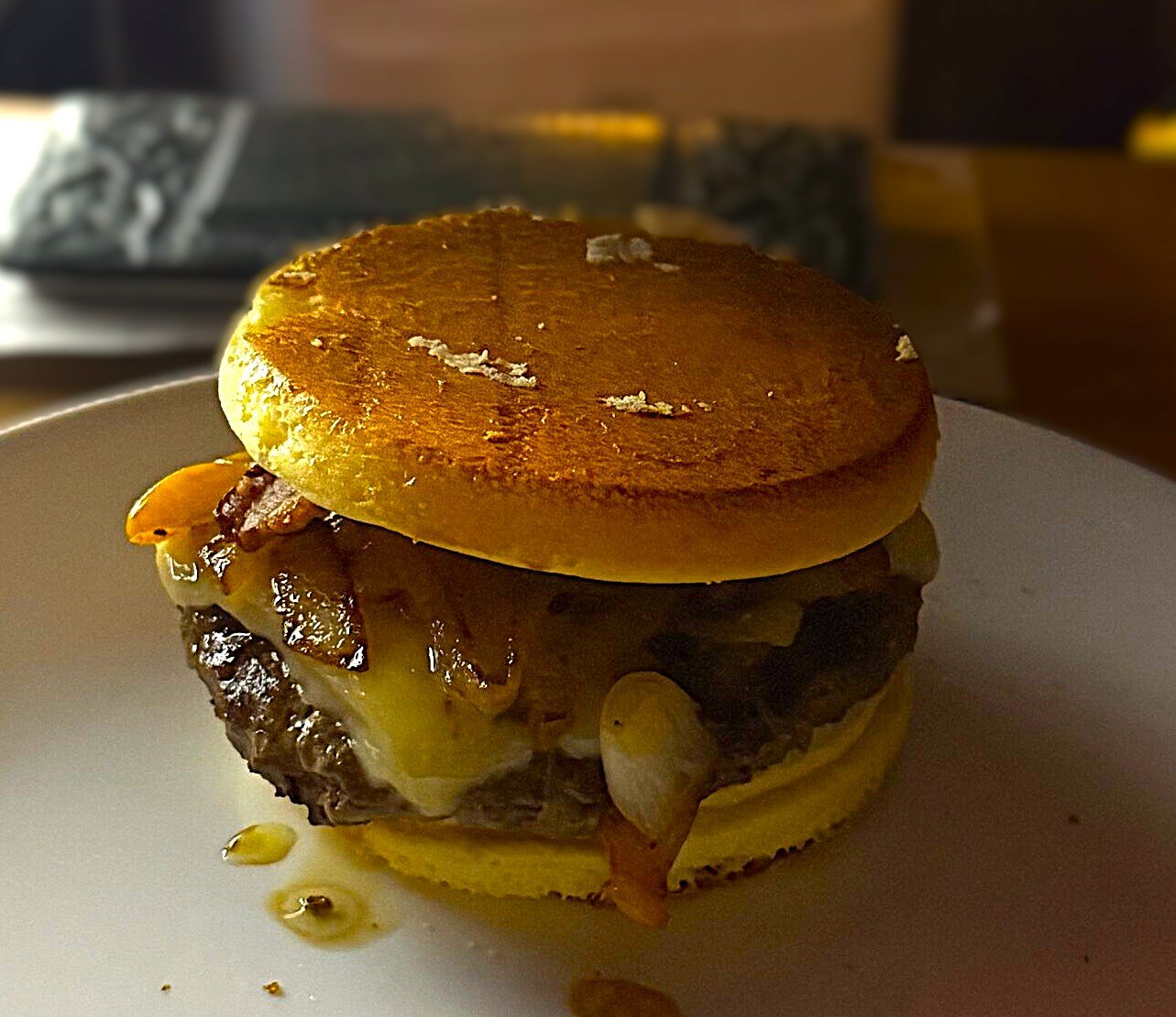 A carnivore-adjacent burger stacked with bacon, pepper jack, and grilled onions and peppers on a golden keto bun